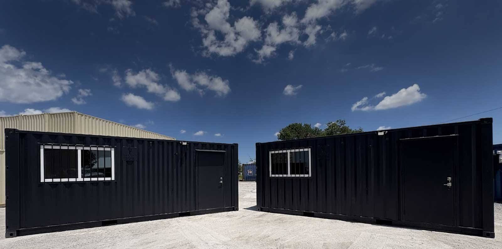 Two black container office conversions built by Cactus Containers, with windows, security bars and steel entry doors, at a Texas yard